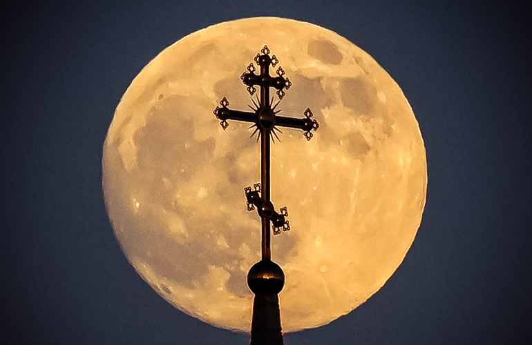 Mặt trăng tròn sau cây thánh giá trên đỉnh một nhà thờ cở thành phố Rossosh, Voronezh, Nga.